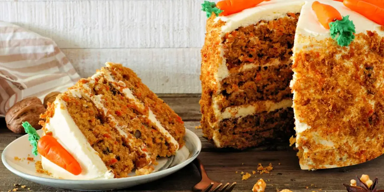 Deliciosa tarta de zanahoria con glaseado cremoso y decoraciones de zanahorias. Una rebanada ya servida en un plato.