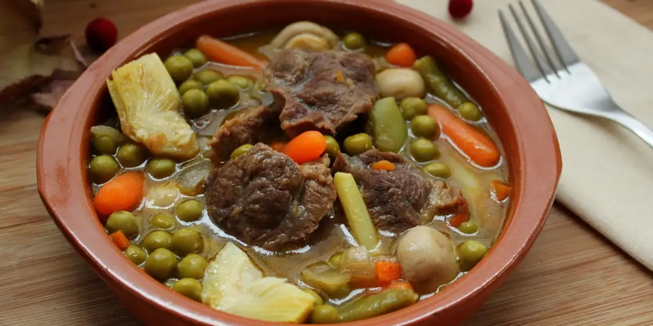 Menestra de verduras con carne, un plato reconfortante con trozos de carne tierna, guisantes, zanahorias y judías verdes en un caldo sabroso.
