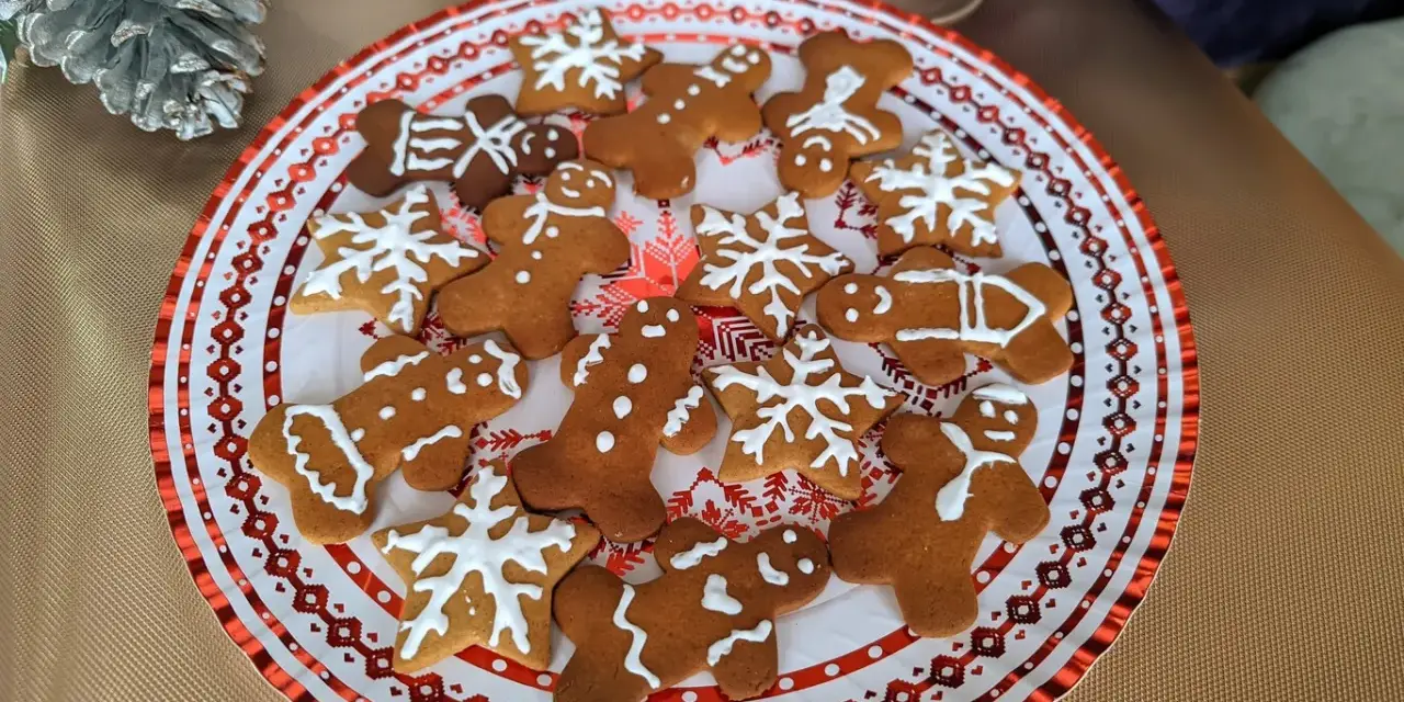 Plato con galletas de jengibre decoradas con glaseado blanco, con formas de hombrecitos, estrellas y copos de nieve. ¡Perfectas para la temporada navideña!