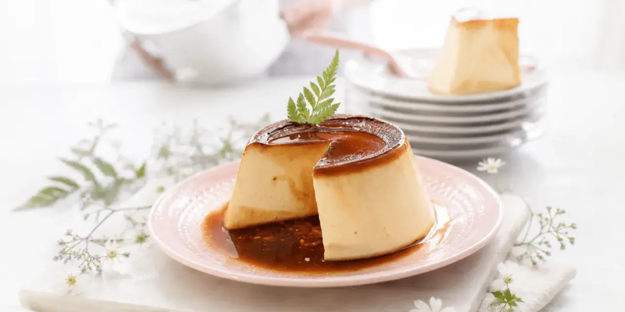Delicioso flan de queso con caramelo líquido, decorado con una ramita verde. Se apilan más porciones en el fondo.