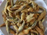 Un plato blanco lleno de boquerones fritos crujientes, listos para disfrutar.