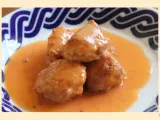 Deliciosas albóndigas de rape en una cremosa salsa naranja, servidas en un plato con borde azul.