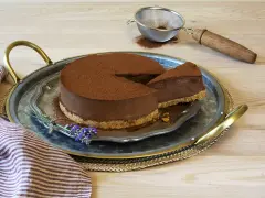 Delicioso pastel de chocolate cubierto de cacao, con una rebanada servida en una bandeja de plata, decorado con lavanda.