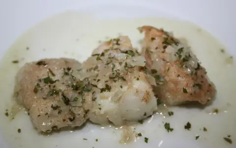 Tres trozos de bacalao en salsa verde, con perejil picado y trocitos de ajo.