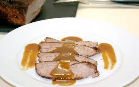 Rabillo de cadera al horno, jugoso y tierno, servido en rodajas con una rica salsa.