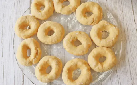 Un plato transparente muestra rosquillas caseras esponjosas, listas para hornear.