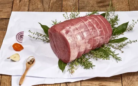 Un añojo ternera, parte de la pierna, listo para asar con hierbas aromáticas, cebolla, zanahoria y especias.