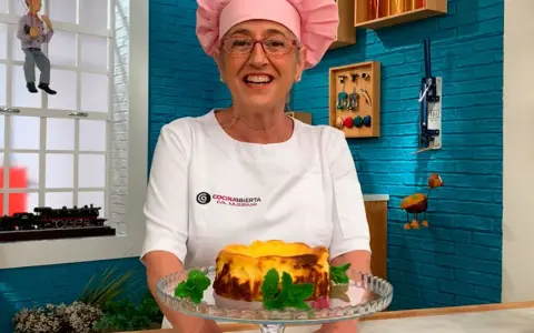 Eva Arguiñano sonríe mostrando una deliciosa tarta de queso casera, decorada con hojas de menta.