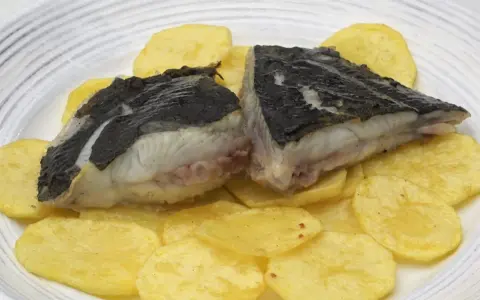 Rodaballo a la plancha, jugoso y tierno, servido sobre patatas fritas crujientes. Un plato sencillo pero delicioso.