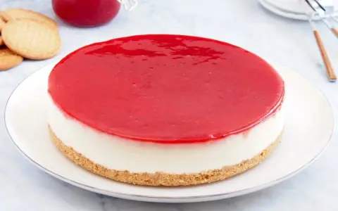 Deliciosa tarta de queso Philadelphia con cobertura roja brillante, lista para disfrutar.