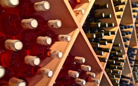 Estanterías de madera llenas de botellas de vino tinto y blanco. Un lugar donde se guarda el vino, listo para ser disfrutado.