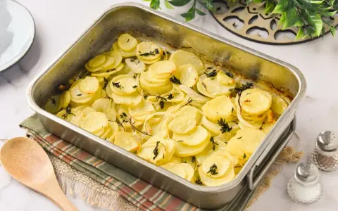 Patatas panaderas recién horneadas, doradas y tiernas, con cebolla y tomillo, listas para servir.