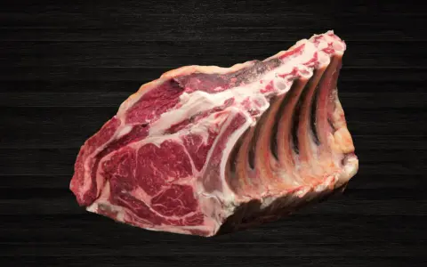 Lomo bajo de vacuno crudo con costillas, sobre fondo oscuro de madera.