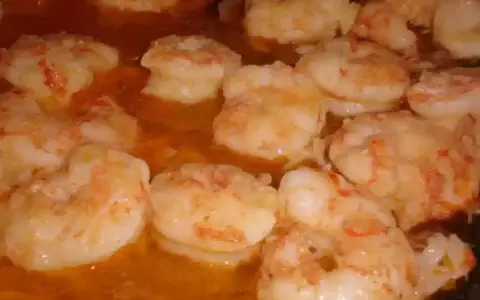 Gambas al pil pil burbujeando en aceite de oliva, listas para ser disfrutadas.