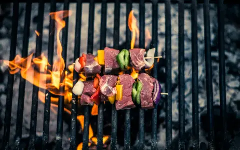 Brochetas de carne y verduras sobre una parrilla con llamas. Así es como se prepara una deliciosa barbacoa.