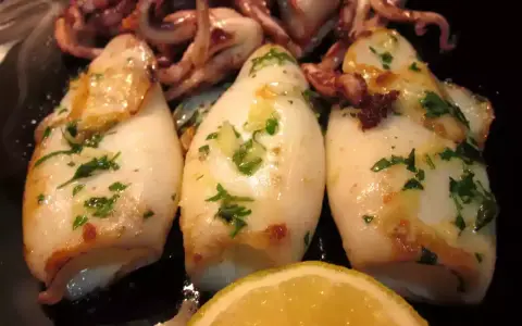Calamares a la plancha, tiernos y dorados, con perejil fresco y un toque de limón. ¡Un manjar para disfrutar!
