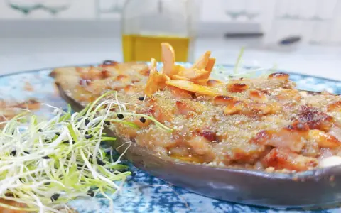 Berenjenas rellenas gratinadas con piñones y brotes frescos, un plato delicioso y nutritivo.