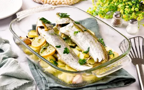 Pescadilla al horno con patatas, limón y ajo, recién salida del horno. Un plato sencillo y delicioso.
