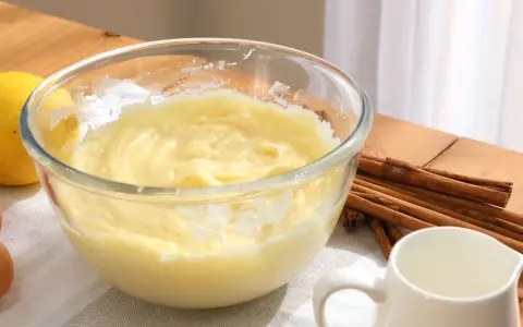 Bol con crema pastelera, huevos, limón y canela. Ingredientes para un postre delicioso.