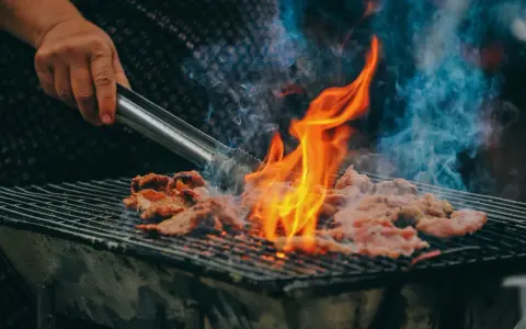 Carne a la parrilla, humeante y chispeante, lista para una deliciosa parrillada barbacoa.