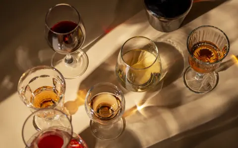 Copas de vino tinto y blanco, y una botella oscura, con reflejos de luz. El vino abierto se pone malo, mejor disfrutarlo pronto.
