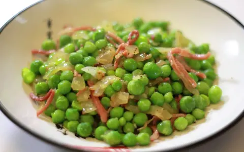 Guisantes con jamón, un plato sencillo y delicioso. Los guisantes frescos se mezclan con trocitos de jamón y cebolla salteada, creando un bocado lleno de sabor.