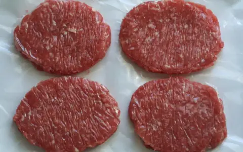 Cuatro hamburguesas de carne poco hecha, listas para cocinar y disfrutar.