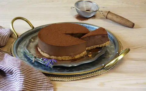 Delicioso pastel de chocolate cubierto de cacao, con una rebanada servida en una bandeja de plata, decorado con lavanda.