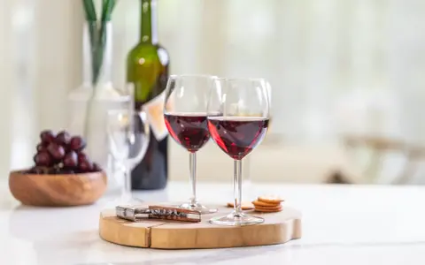 Dos copas de vino tinto, uvas y galletas, listas para disfrutar de un momento especial con los productos de la cooperativa do val.