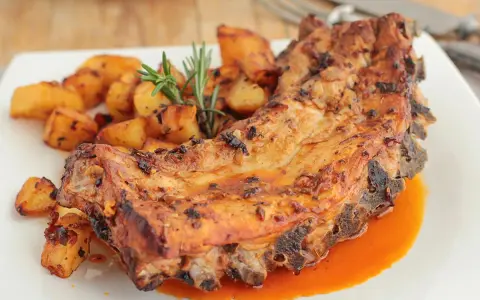 Costillas al horno con patatas doradas y romero fresco. Un plato jugoso y lleno de sabor.
