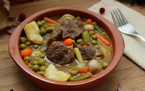 Menestra de verduras con carne, un plato reconfortante con trozos de carne tierna, guisantes, zanahorias y judías verdes en un caldo sabroso.