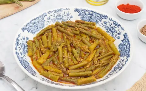 Espárragos esparragados en un plato con diseño azul y blanco, acompañados de pimentón y comino.