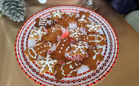 Plato con galletas de jengibre decoradas con glaseado blanco, con formas de hombrecitos, estrellas y copos de nieve. ¡Perfectas para la temporada navideña!