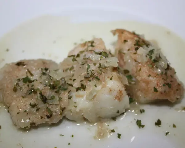 Tres trozos de bacalao en salsa verde, con perejil picado y trocitos de ajo.