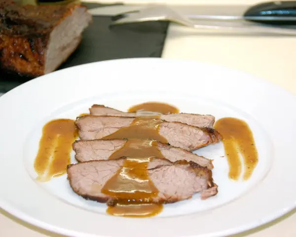 Rabillo de cadera al horno, jugoso y tierno, servido en rodajas con una rica salsa.