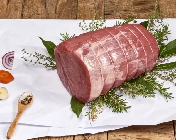 Un añojo ternera, parte de la pierna, listo para asar con hierbas aromáticas, cebolla, zanahoria y especias.