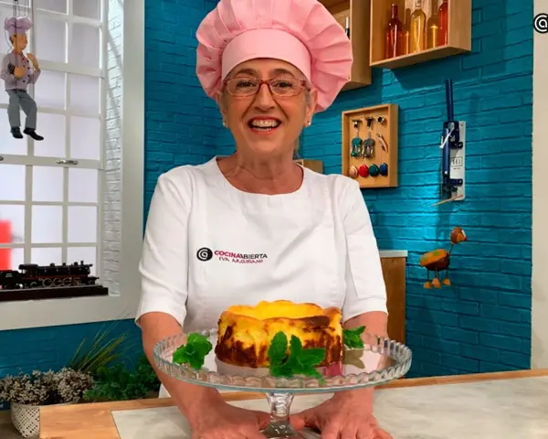 Eva Arguiñano sonríe mostrando una deliciosa tarta de queso casera, decorada con hojas de menta.