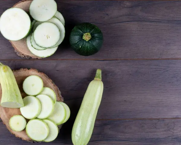 Rodajas de calabacín y calabacines enteros, listos para preparar deliciosas recetas con calabacín.