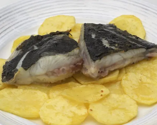 Rodaballo a la plancha, jugoso y tierno, servido sobre patatas fritas crujientes. Un plato sencillo pero delicioso.