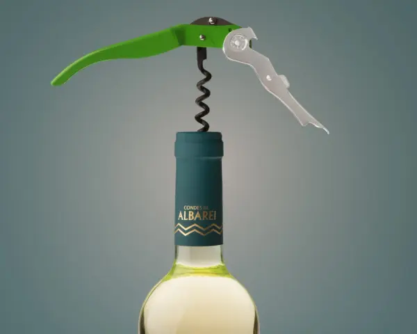 Sacacorchos verde y plateado sobre una botella de vino blanco "Condes de Albarei". El sacacorchos está listo para extraer el corcho, recordándonos de donde viene el corcho.