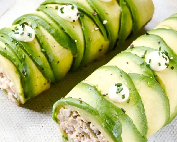 Rollos de aguacate rellenos, perfectos para recetas con aguacate. Decorados con puntos de crema y cebollino.