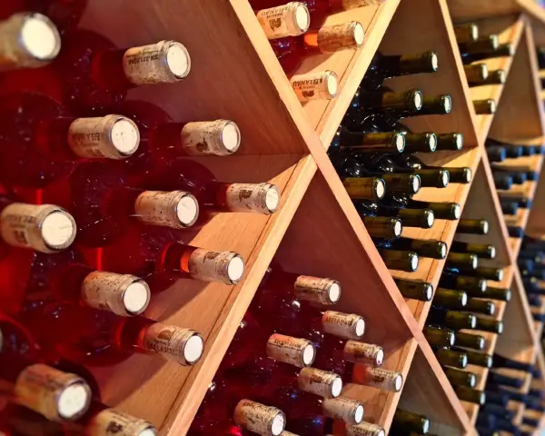 Estanterías de madera llenas de botellas de vino tinto y blanco. Un lugar donde se guarda el vino, listo para ser disfrutado.