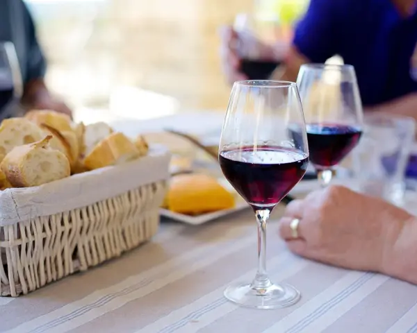 Copa de vino tinto y pan en cesta, disfrutando de un momento en la abadia Mantrus.