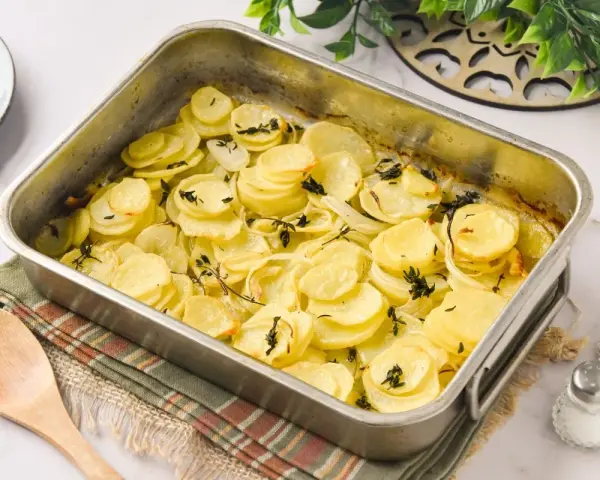 Patatas panaderas recién horneadas, doradas y tiernas, con cebolla y tomillo, listas para servir.