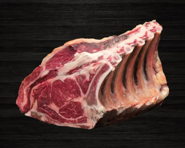 Lomo bajo de vacuno crudo con costillas, sobre fondo oscuro de madera.