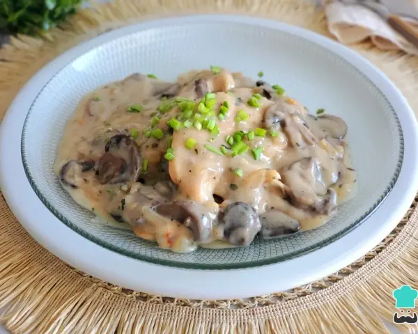 Pollo con champiñones en cremosa salsa de vino blanco, adornado con cebollino fresco. Un plato delicioso y reconfortante.