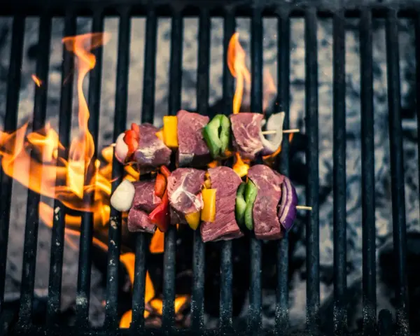 Brochetas de carne y verduras sobre una parrilla con llamas. Así es como se prepara una deliciosa barbacoa.