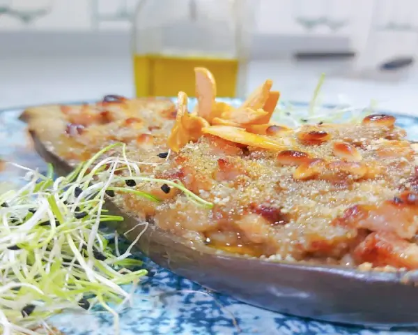 Berenjenas rellenas gratinadas con piñones y brotes frescos, un plato delicioso y nutritivo.