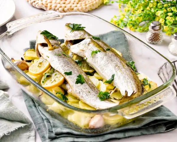 Pescadilla al horno con patatas, limón y ajo, recién salida del horno. Un plato sencillo y delicioso.