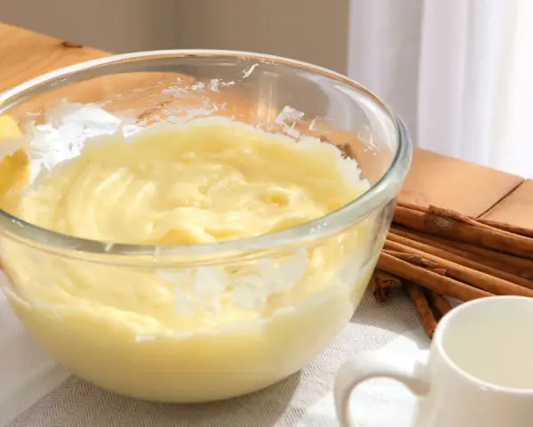 Bol con crema pastelera, huevos, limón y canela. Ingredientes para un postre delicioso.
